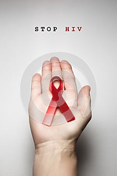 Red ribbon awareness on woman human hand aged white background: