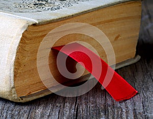 Red ribbon bookmark in closed old book