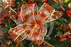 Red ribbon bow on green fir tree branch. Christmas tree ornament close photo with text place