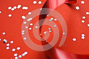 Red ribbon and glitter stars on a red background