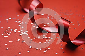 Red ribbon and glitter stars on a red background