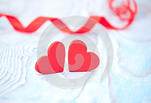 Red ribbon heart and two hearts on blue wooden background on valentine day.