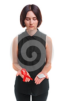 A girl holding a condom and a red ribbon isolated on a white background. Medical support. Safe sex propaganda concept.