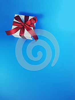 The red ribbon present or gift box in blue background. Christmas or birthday present and thanksgiving, more give the more receive