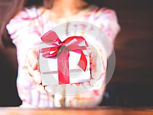 The red ribbon present or gift box in woman hands. Christmas or birthday present and thanksgiving, more give the more receive