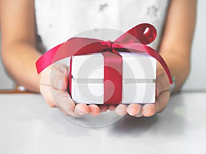 The red ribbon present in a small child`s hands. Christmas or birthday present and thanksgiving, more give the more receipt