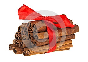 Red ribbon wrapped cinnamon sticks isolated on white background