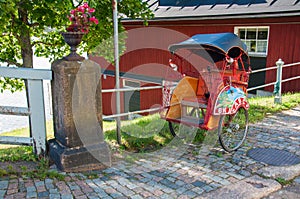 Red rickshaw on a background of red wooden building