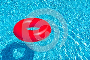 Red ring floating in blue swimming pool. Inflatable ring, rest concept