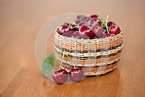 Red Ripe Cherries in a basket on a wood table