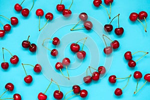 Red ripe cherry berries on blue background. Cherry pattern. Flat lay. Healthy food concept