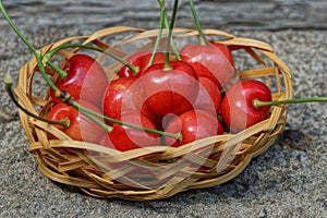 Red ripe cherry berries in a small wooden decorative basket