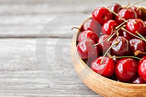 Red ripe cherry berries in wooden bowl. Food background