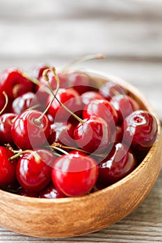 Red ripe cherry berries in wooden bowl. Food background