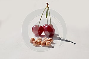 Red ripe cherry and lots of cherry pits on a gray textured background.