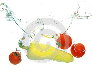Red ripe cherry tomatoes and green paper under water spash on white