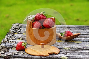 Red ripe strawberries in a wooden basket on the old boards on the background