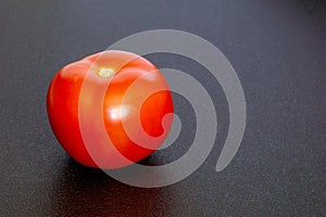 Red ripe tomato on a black texture background