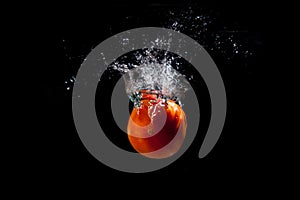 A red ripe tomato falls into the water