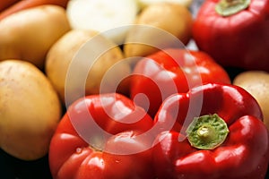 Red ripe tomatoes, red sweet peppers and potato tubers in defocus