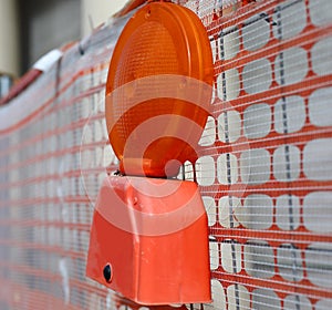 red road construction lamp on fence indicating attention to work in progress