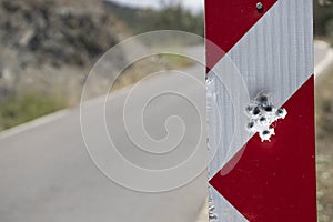 Red road traffic sign full of bullet holes. Close up