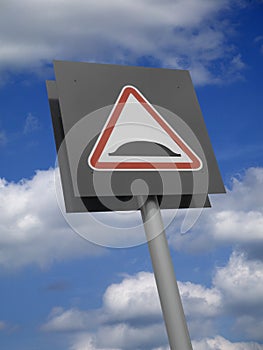 RED ROAD TRAFFIC SPEED BUMP SIGN ON BLUE SKY AND CLOUD BACKGROUND