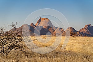 Red rock illuminated with a sunray, in a dry field in Spitzkoppe, Namibia, on a sunny day