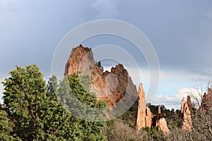 Red Rock pinnacles and evergreen trees against a cloudy, stormy sky at Garden of the Gods in Colorado