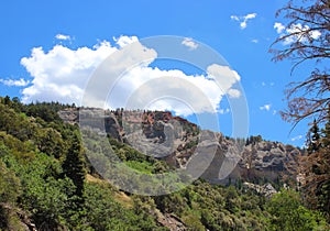 Red rock rock formation with pine tress, brush under brilliant blue skies. Cedar City, Southern Utah