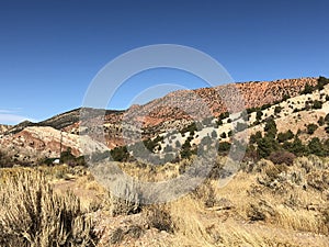 Red rock rock and limestone hills hills with pine tress, brush under brilliant blue skies. Cedar City, Southern Utah