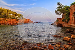 Red rocks beach, rocky coast at sunset in Southern France, French Riviera.