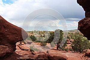 Red rocks, hills and dirt with evergreen trees on the Siamese Twins Trail at Garden of the Gods in Colorado