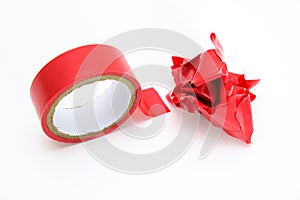 Red roll and a lump of crumpled used electrical sticky isolation duct tape on white background