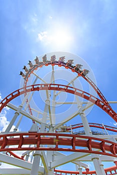 Red roller coaster rail with blue sky in background