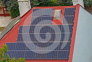 Red roof of a house with lots of solar panels generating electricity .