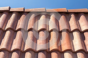 Red roof tile pattern over blue sky.