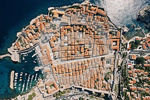 Red roofs of ancient houses in the port with moored boats. Dubrovnik, Croatia. Drone