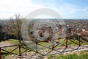 The red roofs of the inhabited houses, the church and the bell tower of the pietrasanta cathedral seen from the green of a hill at