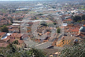 The red roofs of the inhabited houses, the church and the bell tower of the pietrasanta cathedral seen from the green of a hill at