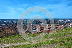 The red roofs of the inhabited houses, the church and the bell tower of the pietrasanta cathedral seen from the green of a hill at