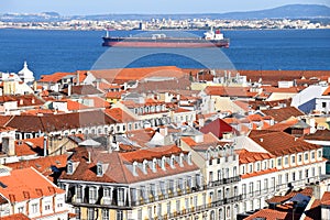Red roofs of Lisbon against the background of a cargo ship sailing on the Tagus River