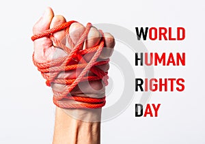 Red rope on fist hand with WORLD HUMAN RIGHTS DAY text on white background