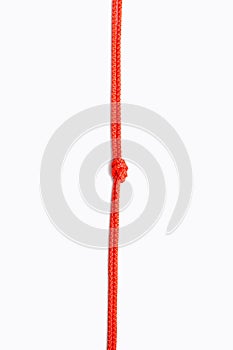 Red rope with a knot in the center on a white vertical background