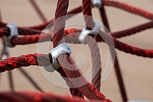 Red rope sections fastened with a metal clamp and a brown sand background