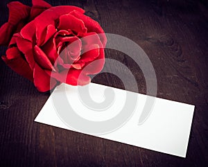 Red rose and blank gift card for text on old wood background