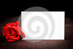 Red rose and blank gift card for text on old wood background