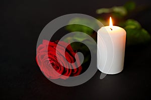 Red rose and burning candle over black background