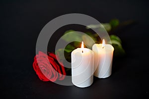 Red rose and burning candles over black background