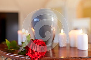 Red rose and cremation urn with burning candles